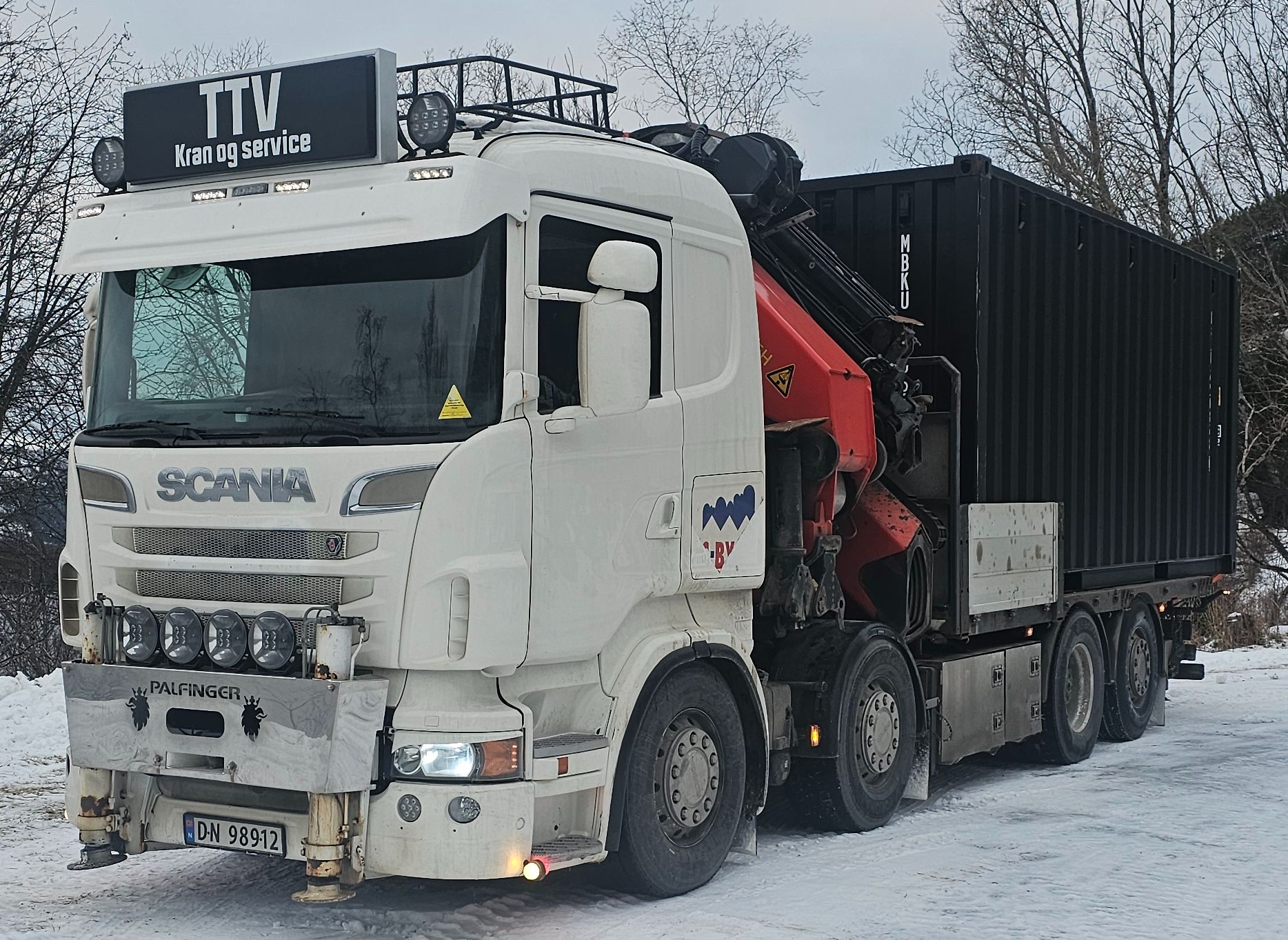 Kranbil med en container på lasteplanet sitt